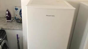 A compact kitchen with a white refrigerator, a washing machine, and a mop. - Featherstone Court (London)