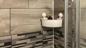 A modern bathroom with a shower, a sink with two faucets, and a decorative tile backsplash. - Featherstone Court (London)