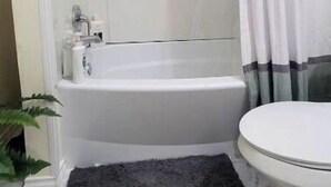 A bathroom with a bathtub, toilet, and shower curtain. - Silver pine one bedroom with a nice patio deck. (Austin)