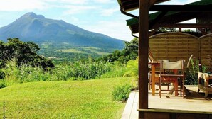 A covered outdoor seating area with a view of a mountain. - Bungalow on a mountainside (Le Morne Rouge)