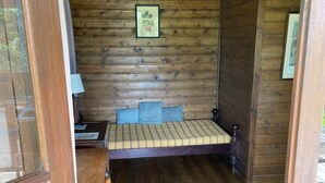A wooden cabin bedroom with a bed, pillows, a nightstand, and a framed picture on the wall. - Bungalow on a mountainside (Le Morne Rouge)