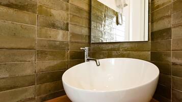 A bathroom with a large white vessel sink, a wooden vanity, and a mirror above the sink.