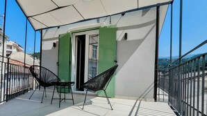 Een balkon met twee zwarte stoelen, een wit plafond en een groene deur.