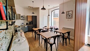 Een moderne keuken met houten kasten, een eethoek met houten tafels en stoelen, hanglampen en uitzicht op het omliggende landschap.