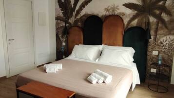 A hotel room with a bed, a wooden nightstand, a small table, and a door.