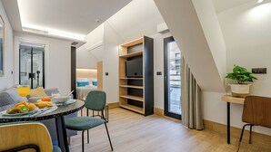 A modern dining area with a table set for breakfast, a sofa, and a bookshelf. - Feelathome Ventas Suites (Madrid)