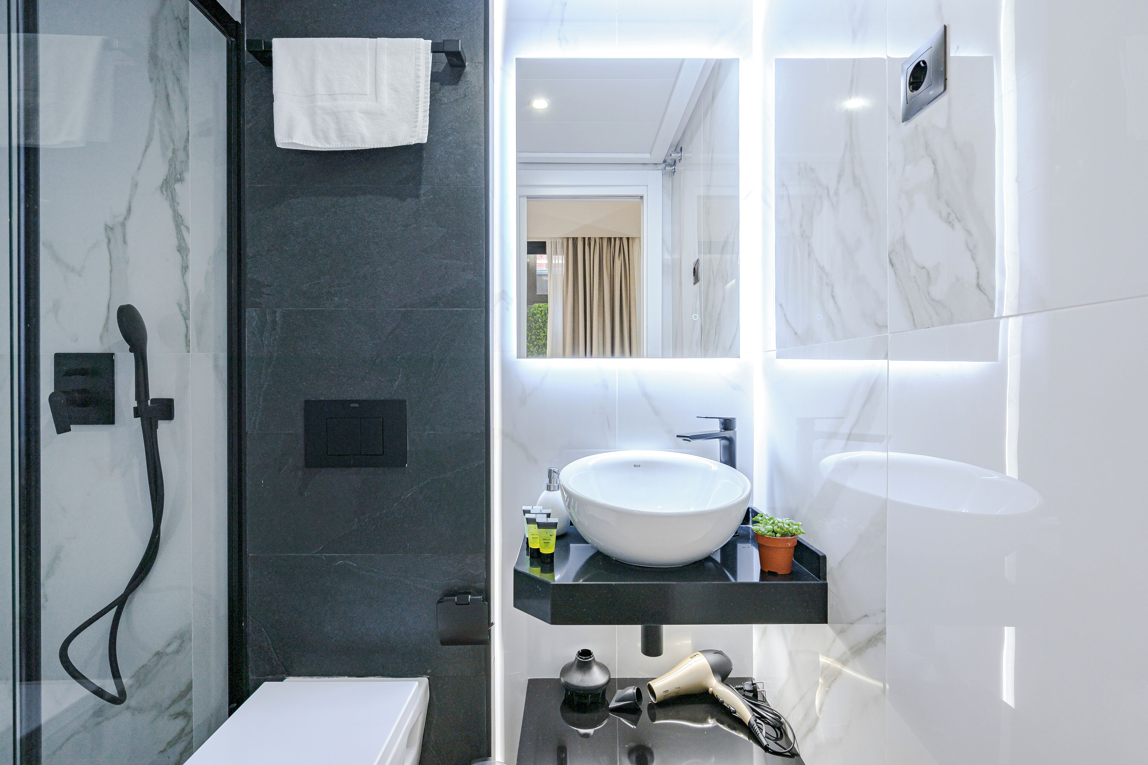 A modern bathroom with a glass-enclosed shower, a white sink, and a mirror.