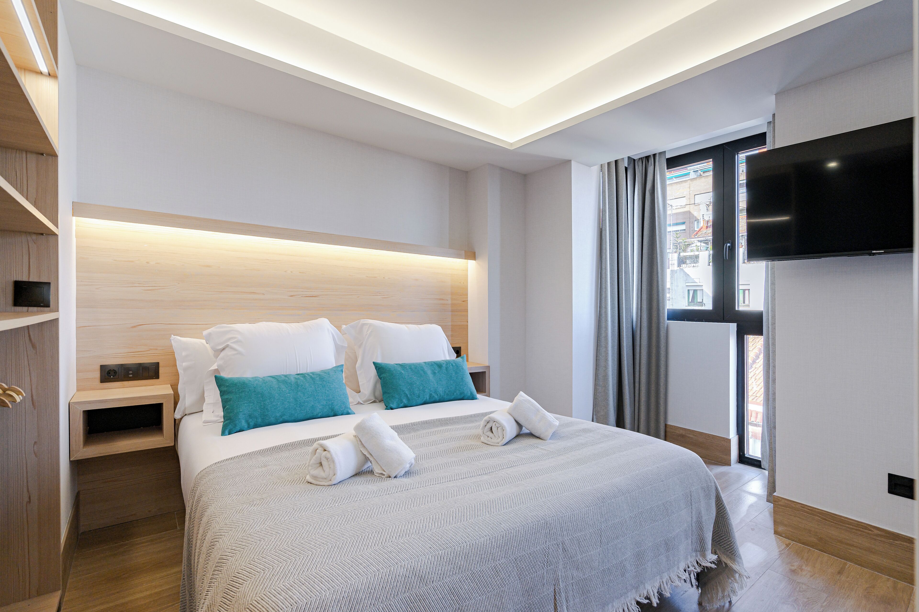 Un hotel moderno con una cama grande, televisión y vistas a la ciudad.