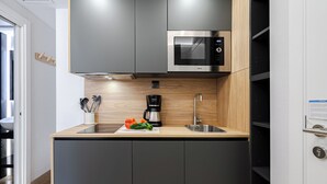 A modern kitchen with a microwave, sink, and wooden countertop. - Feelathome Ventas Suites (Madrid)