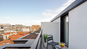 A balcony with a potted plant, two chairs, and a fruit bowl. - Feelathome Ventas Suites (Madrid)
