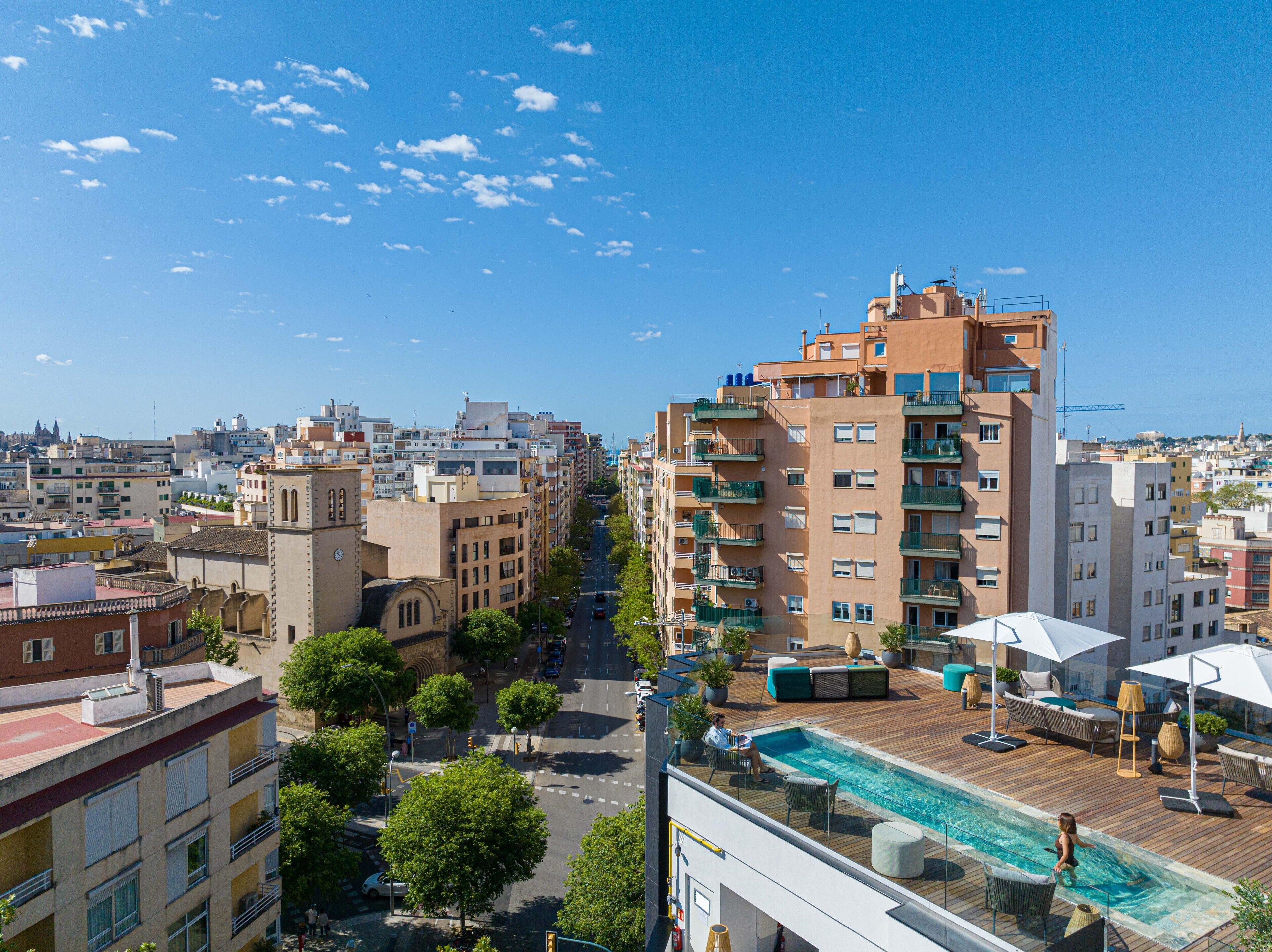 Un edificio alto con piscina en la azotea, que cuenta con zona de estar al aire libre y vistas despejadas de la ciudad.