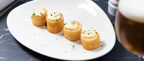 Ein Esstisch mit einer Platte Mini-Quiches, einem Salz- und Pfefferstreuer, einem Weinglas und einer Gabel auf einem Servietttuch.