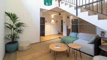 Un interior moderno con una escalera, un sofá, una mesa de centro y una planta en maceta.
