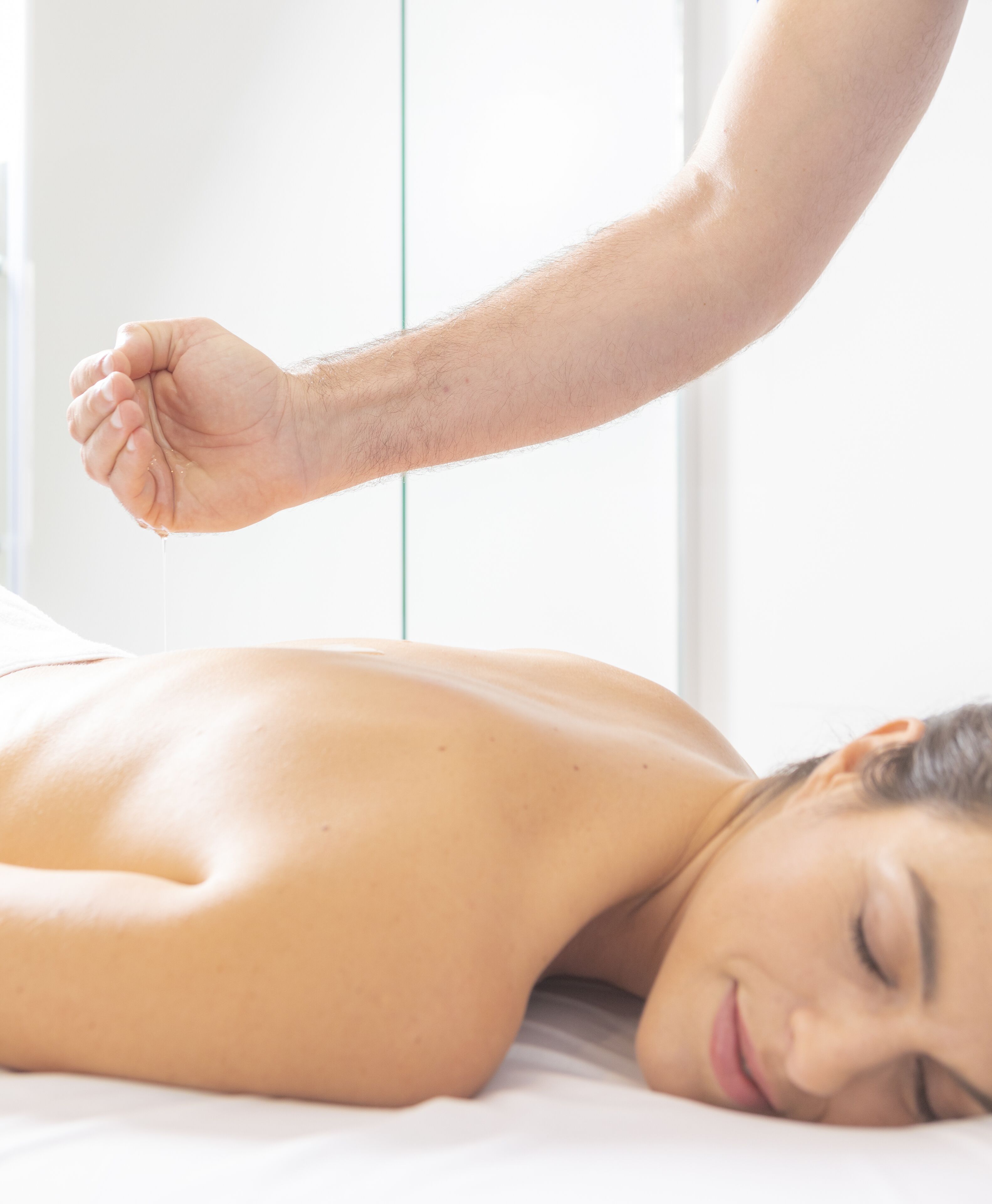 A person lying on a bed receiving a back massage.