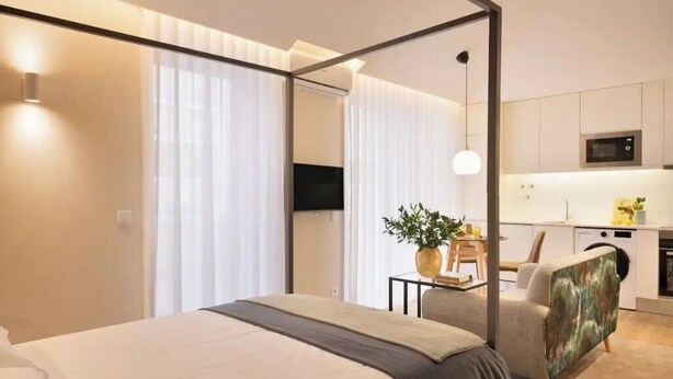 Una habitación de hotel moderna con una cama grande, un comedor y una kitchenette.