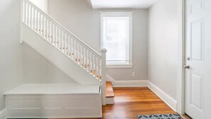 Un escalier avec des rampes blanches et un plancher en bois menant à un palier.