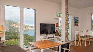 A modern living room with a large TV, wooden table, and comfortable seating.