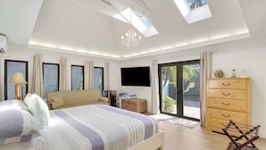 A bedroom with a bed, a TV, a dresser, and a skylight. - Waterfront! Boat Dock and Guesthouse (North Palm Beach)