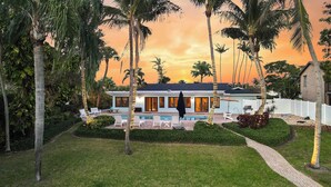 A modern house with a swimming pool, surrounded by palm trees and a well-maintained lawn. - Waterfront! Boat Dock and Guesthouse (North Palm Beach)
