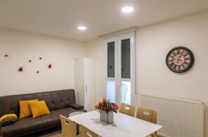Cozy living space with a leather sofa, dining table, and vase with flowers.
