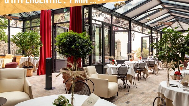 Een restaurant met een glazen patio, tafels, stoelen en potplanten.