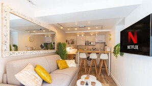 Een moderne woonkamer met een bank, een salontafel en een aan de muur bevestigde televisie.