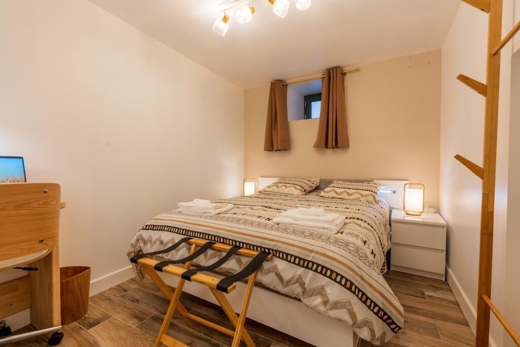 Une chambre à coucher avec un lit, des tables de chevet, une chaise en bois, une petite table et un miroir.