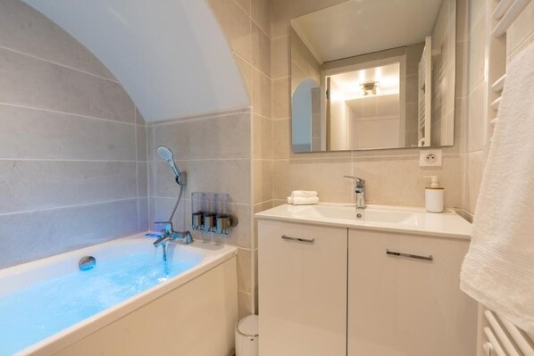 Un baño moderno con bañera, lavabo y espejo.