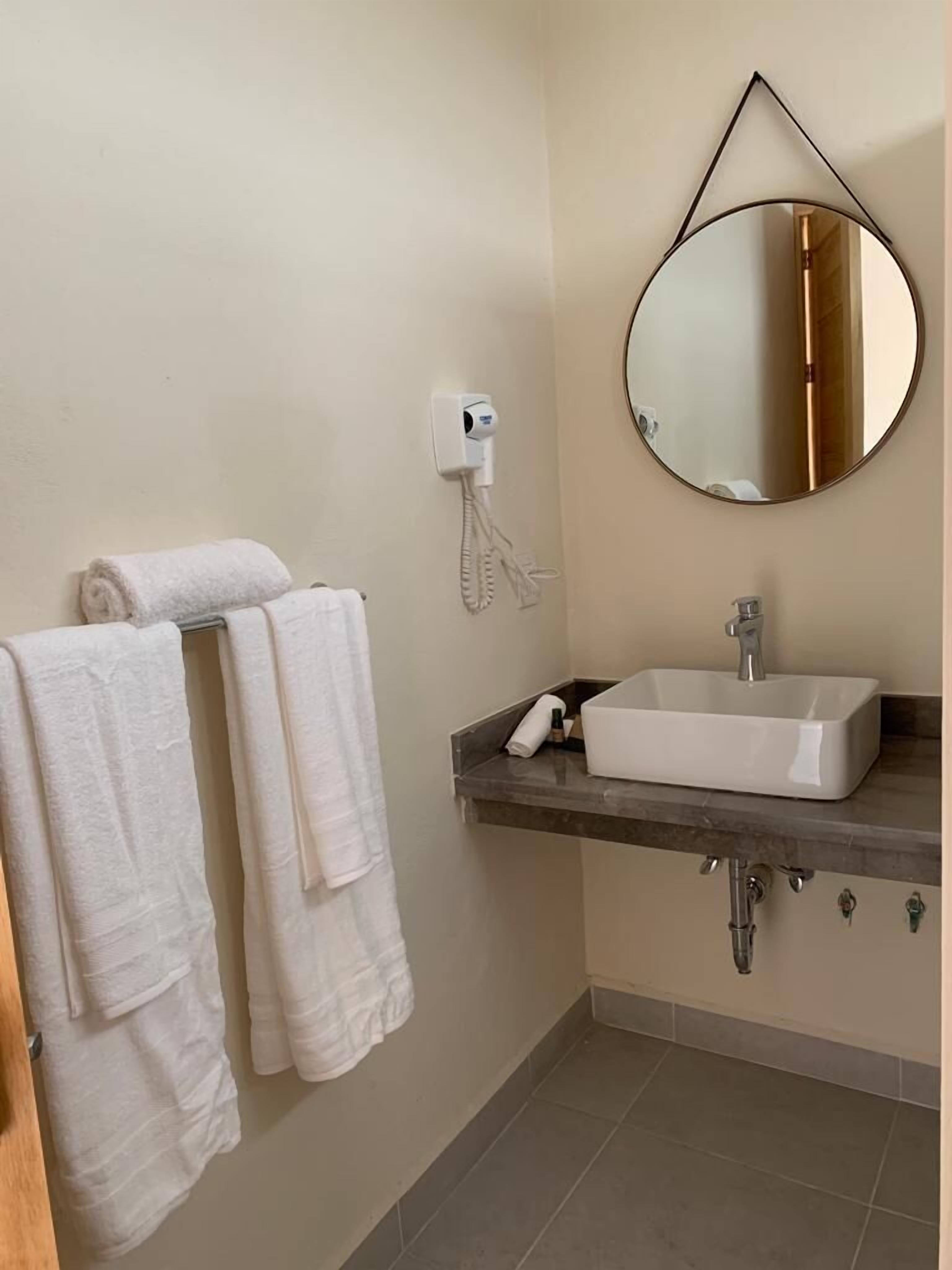A bathroom with a white sink, a mirror, and two towels hanging on the wall.