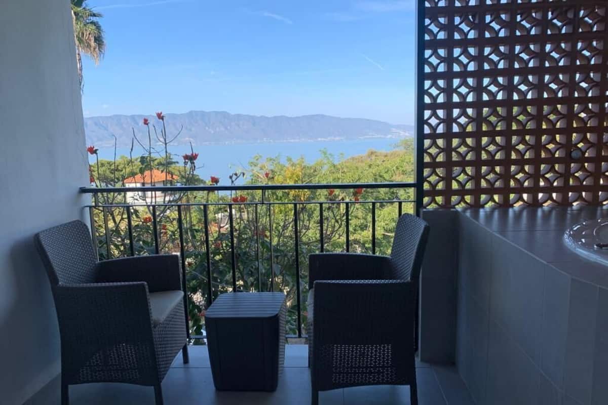 Un balcón con mobiliario de mimbre, vista al mar y celosía decorativa.