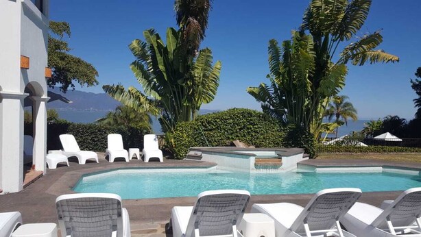 A pool area with lounge chairs, a hot tub, and tropical plants. - Casa Rivera de Moras (Tuxcueca)