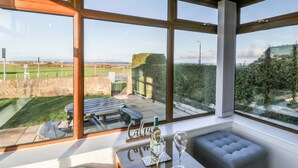 A room with large windows offering a view of a golf course and a stone wall.