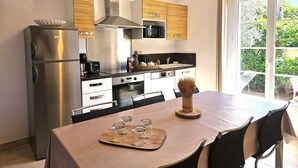 Et moderne køkken med stålemmer, et spisebord med stole og udsigt ud af vinduet.