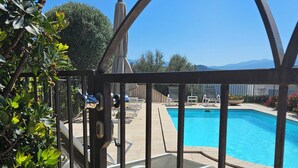 A pool area with a clear view through a metal gate, including a pool, lounge chairs, and a mountain backdrop. - Acqua è Terra Special Offer: Air Conditioning, Pool & Garden, 5-minute walk from St. Florent (Saint-Florent)