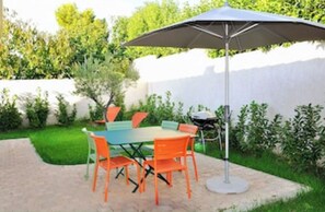 Enjoy dining or socializing in the garden patio with a shaded table and comfortable seating.