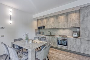 A modern kitchen with grey cabinets, a built-in microwave, and a stove.
