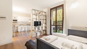 Habitación de hotel moderna con cama, televisor, escritorio y silla, y vista al exterior.