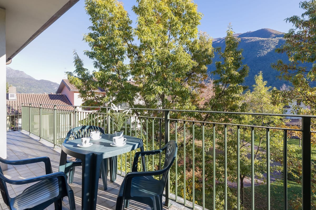 Ein Balkon mit Tisch und Stühlen mit Blick auf eine gebirgige Landschaft.