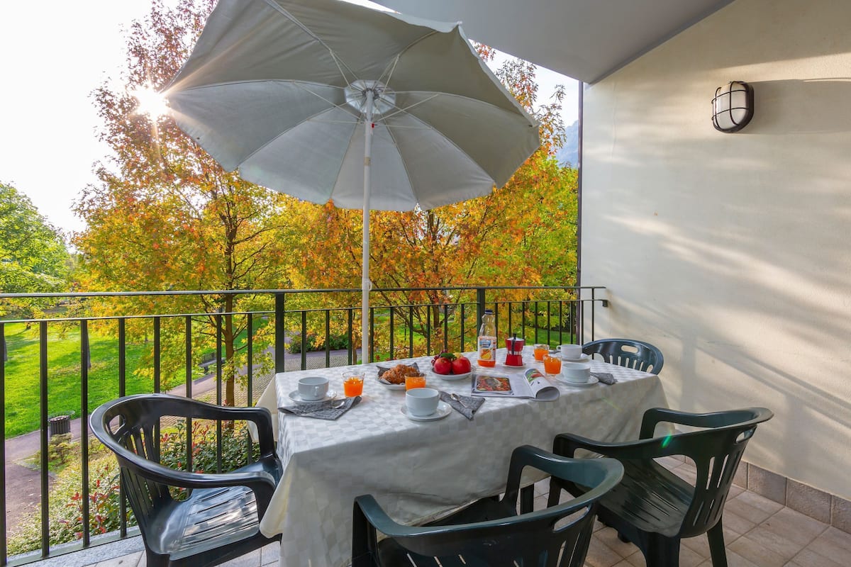 Ein Balkon mit Frühstückstisch, einschließlich Tellern, Tassen und einer Orangensaftflasche.