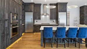 Une cuisine moderne avec des meubles en bois foncé, des appareils en acier inoxydable et un îlot central doté de tabourets de bar.