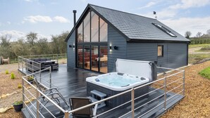 Una casa moderna con terraza, jacuzzi y un amplio ventanal que da a una sala de estar.