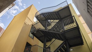 Un escalier métallique à plusieurs niveaux, avec une façade jaune.