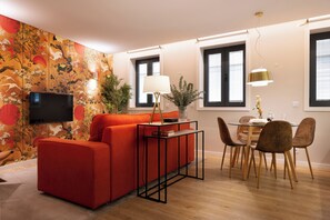 A modern living room with a red sofa, a glass coffee table, and a dining area with wooden chairs and a table.