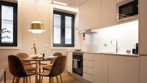 Une cuisine moderne avec un coin repas, comprenant une table avec des chaises, un luminaire suspendu, une cuisinière et un four à micro-ondes.