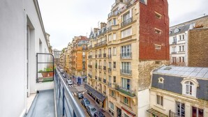 Une rue étroite, bordée de bâtiments des deux côtés, avec des balcons et un trottoir pour les piétons.