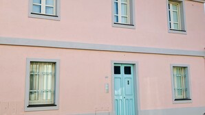 A pink building with three windows and a door, each with white frames and light blue shutters. - ARRUBIU - small but comfy, perfect for singles, couples w. small children (P3399 (Cabras)