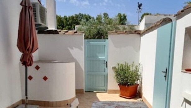 A patio with a table and chairs, a potted plant, and a blue door. - ARRUBIU - small but comfy, perfect for singles, couples w. small children (P3399 (Cabras)