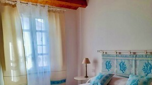 Um quarto com cama, cortinas, luminária e teto de madeira.