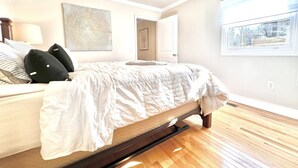 Un dormitorio con cama, ventilador de techo, ventana con vistas y una puerta.