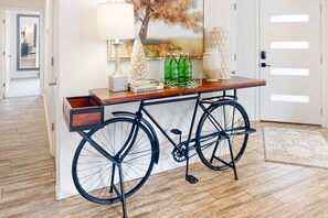 Una habitación con un escritorio de madera, una bicicleta, un árbol de Navidad y un cuadro en la pared.
